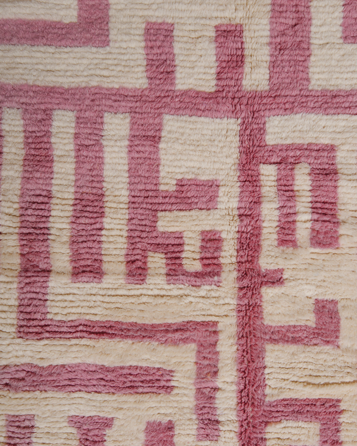 Texture of azilal rug made of soft sheep's wool in natural cream and rose. 