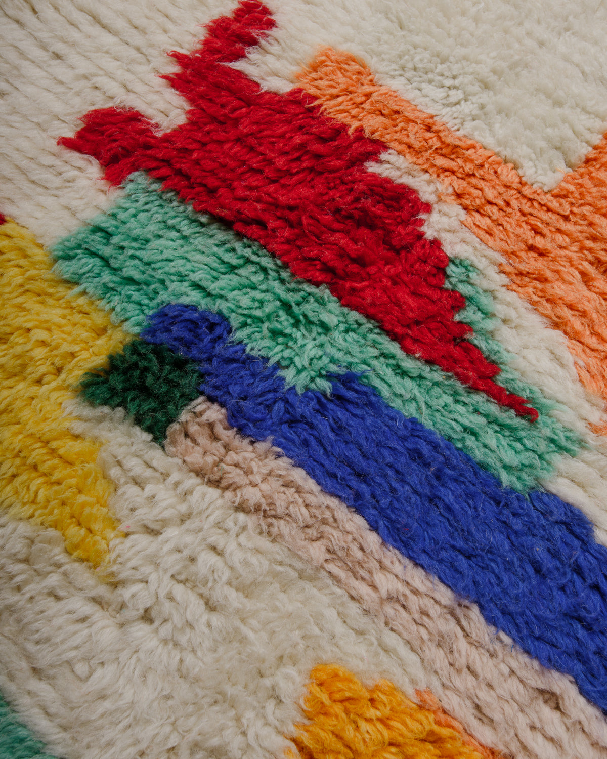 Surface of wool rug featuring red, blue, turquoise, yellow, orange and green wool.