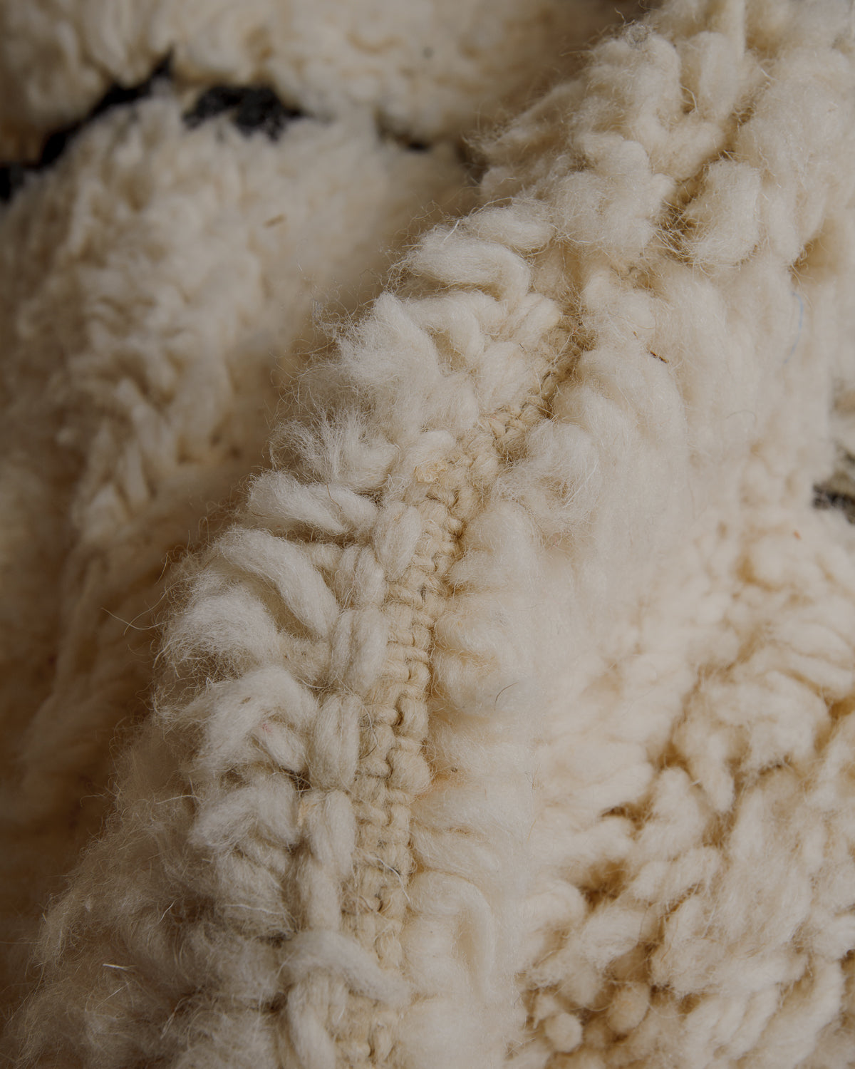 Fluffy cream wool pile with black lines.