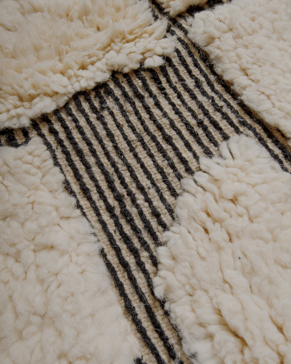 Close up of embroidered black details between cream pile.