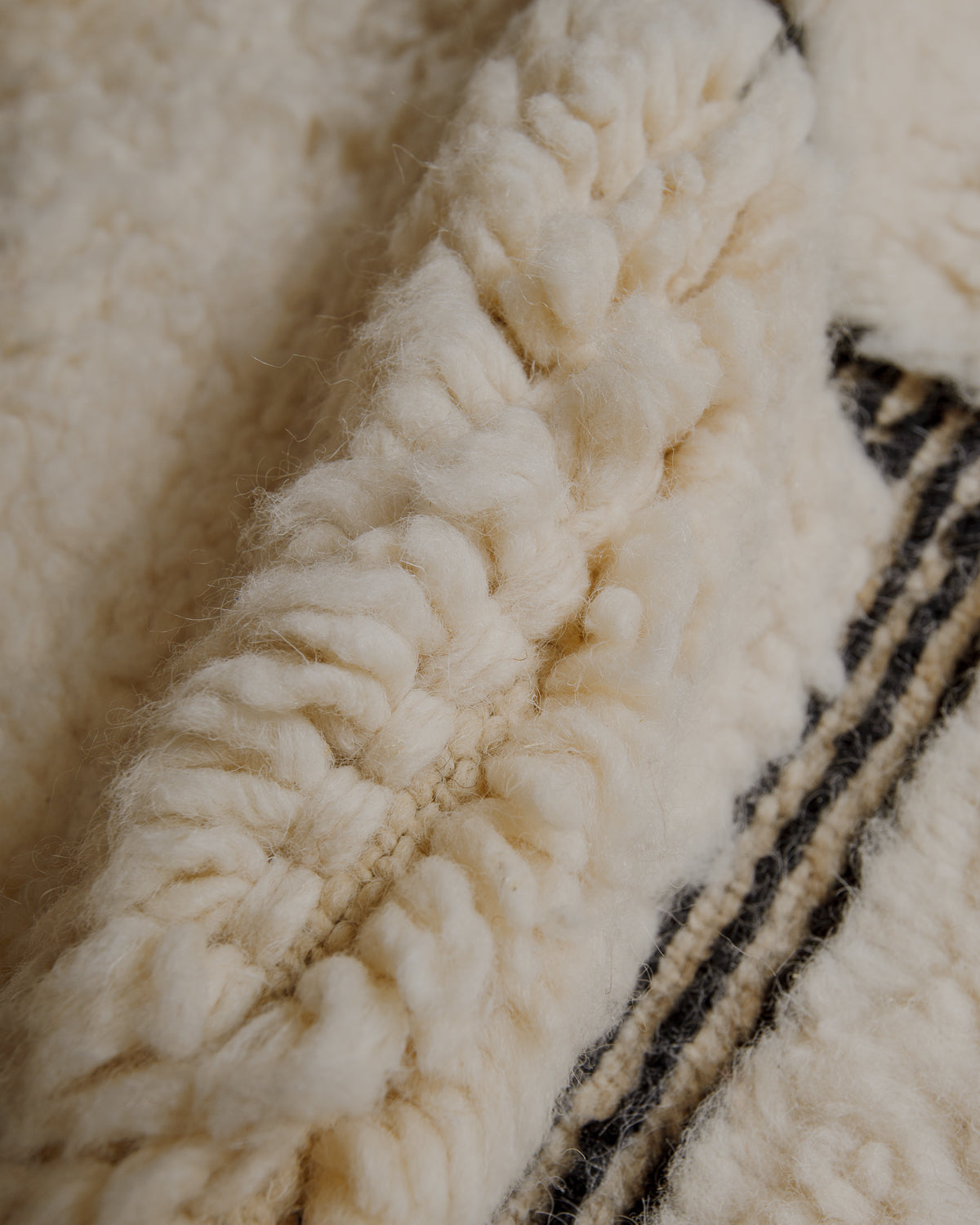 Fluffy cream wool pile with black lines.