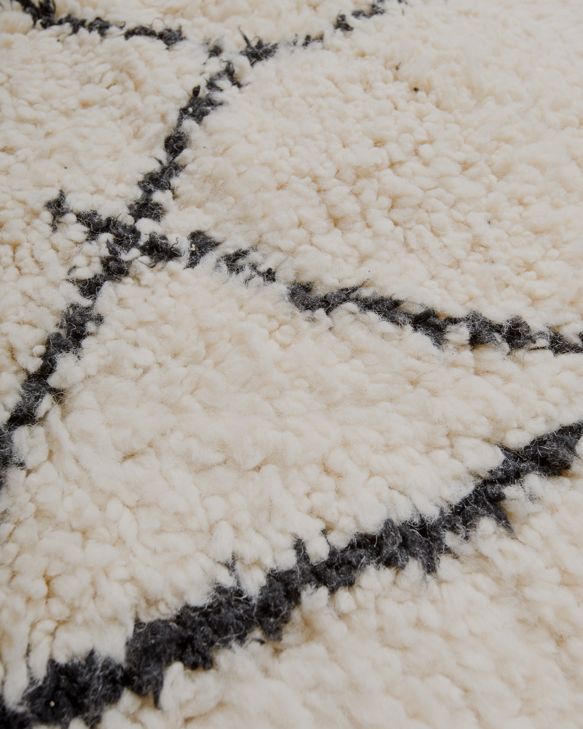 Surface of cream wool rug with black lines.