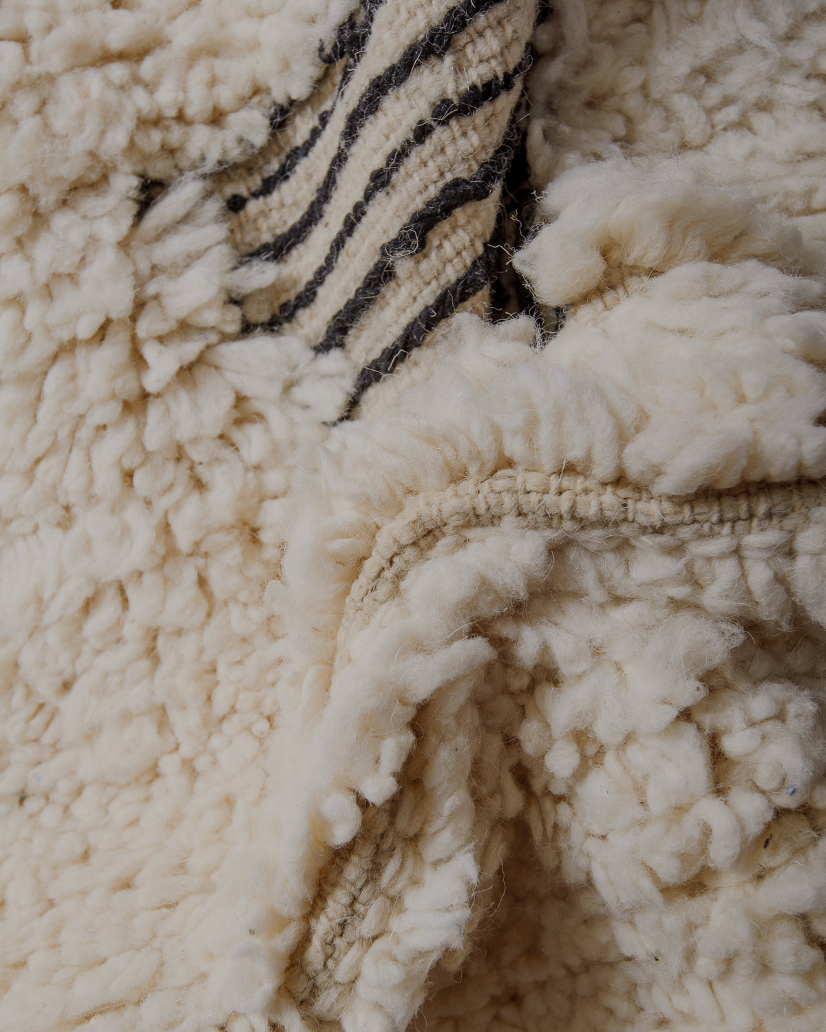 Fluffy cream wool pile with black lines  embroidered.
