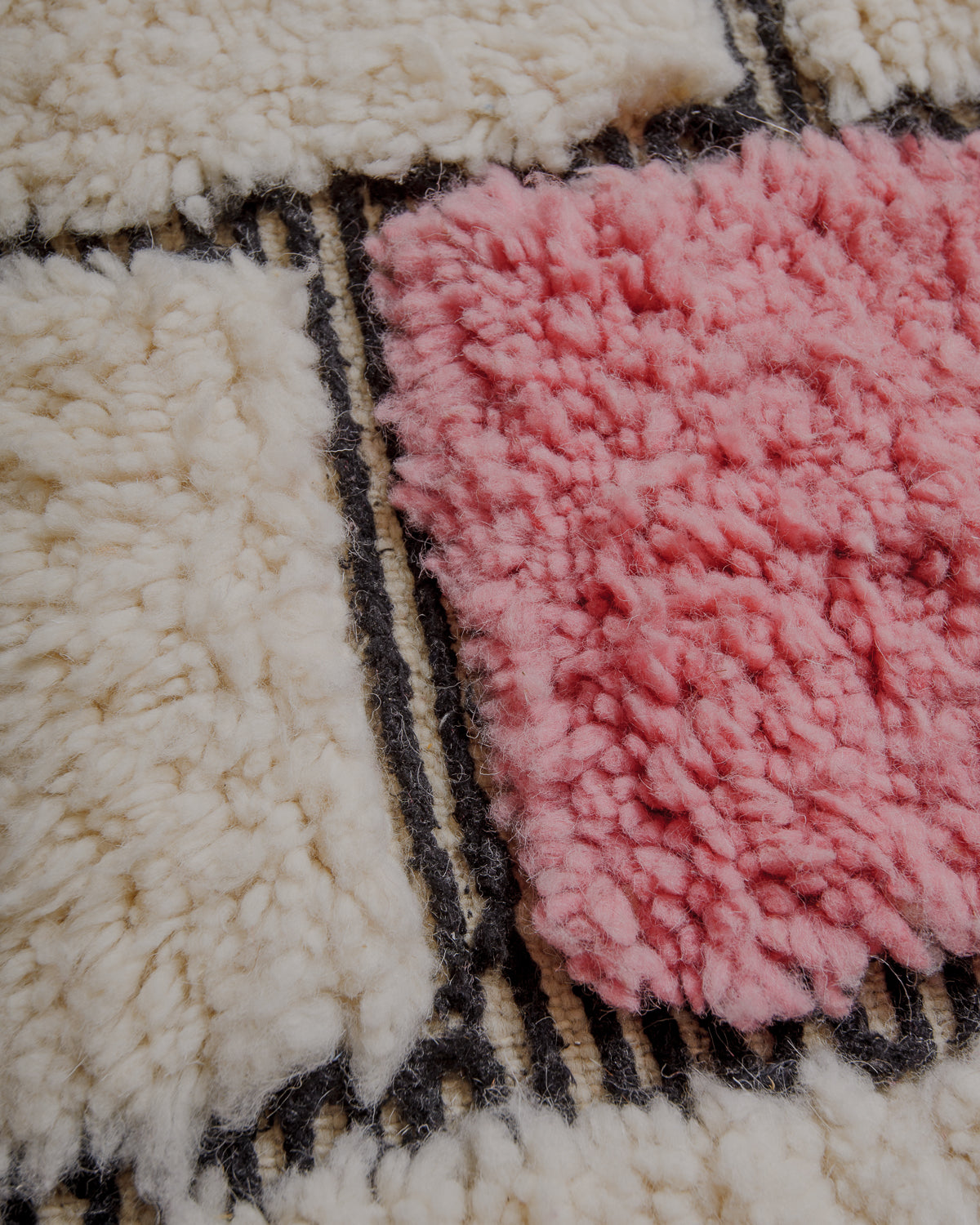 Fluffy cream wool pile with pink and black details.