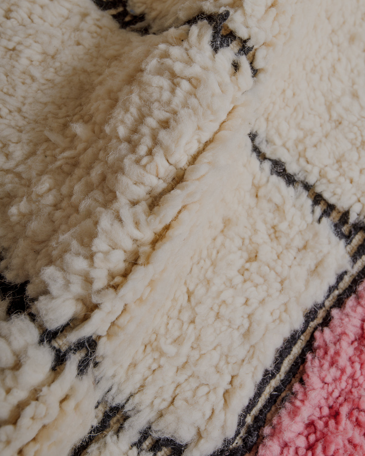 Fluffy cream wool pile with pink and black details.
