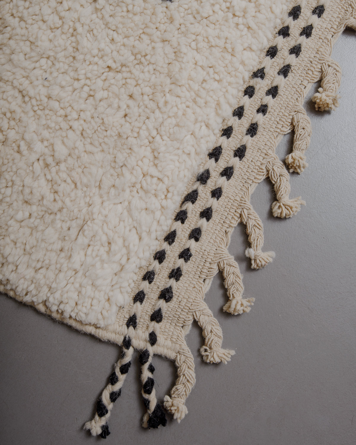 Edge of cream beniourain rug with natural wool tassels.
