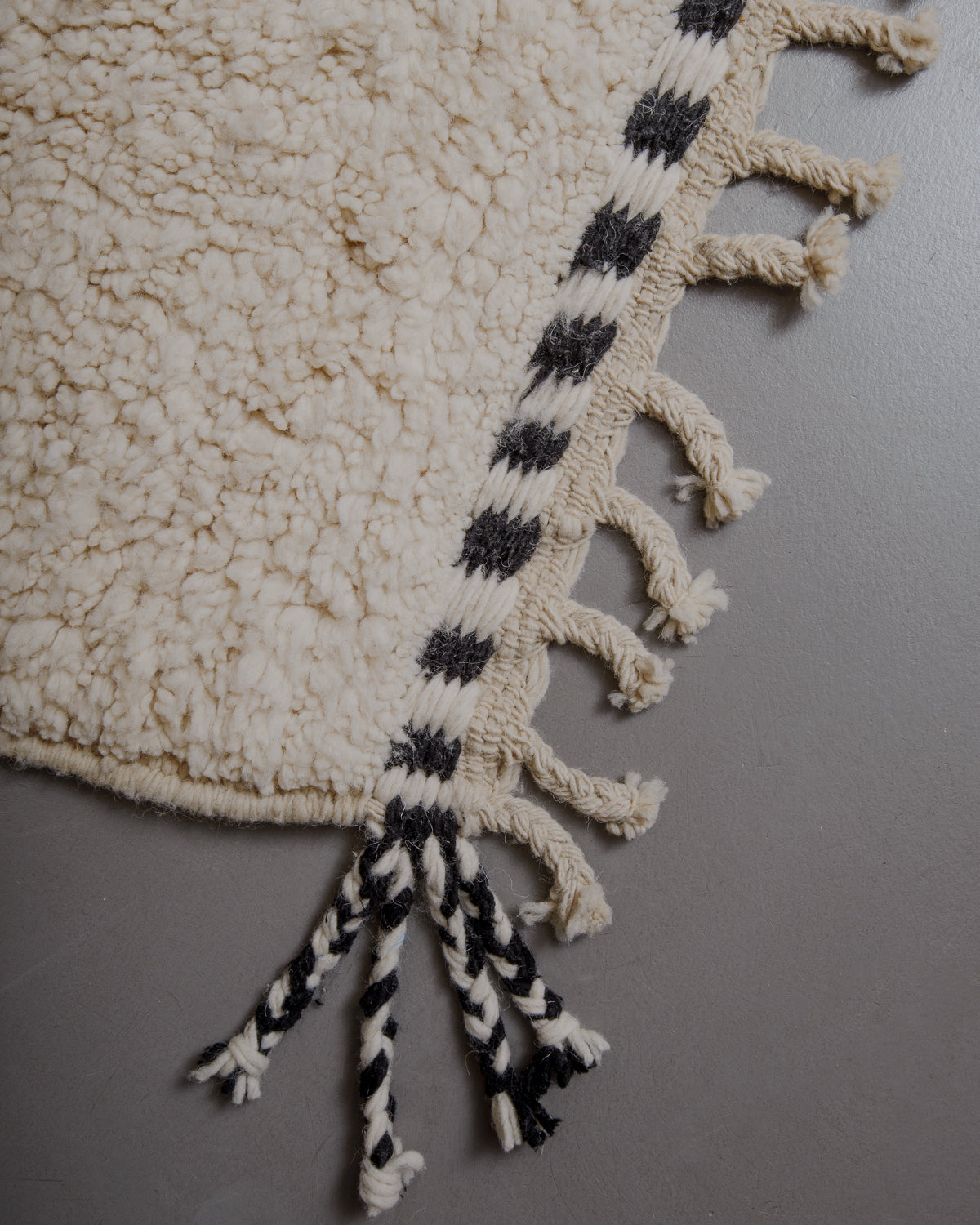 Edge of cream beniourain rug with natural wool tassels.