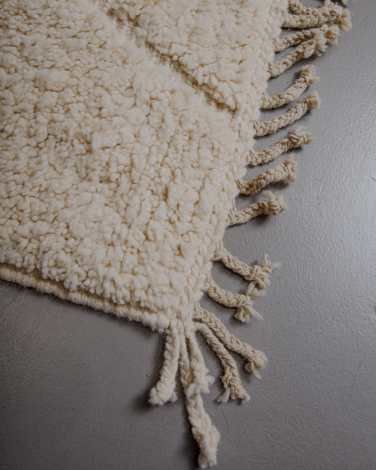 Corner of cream beniourain rug with natural wool tassels.