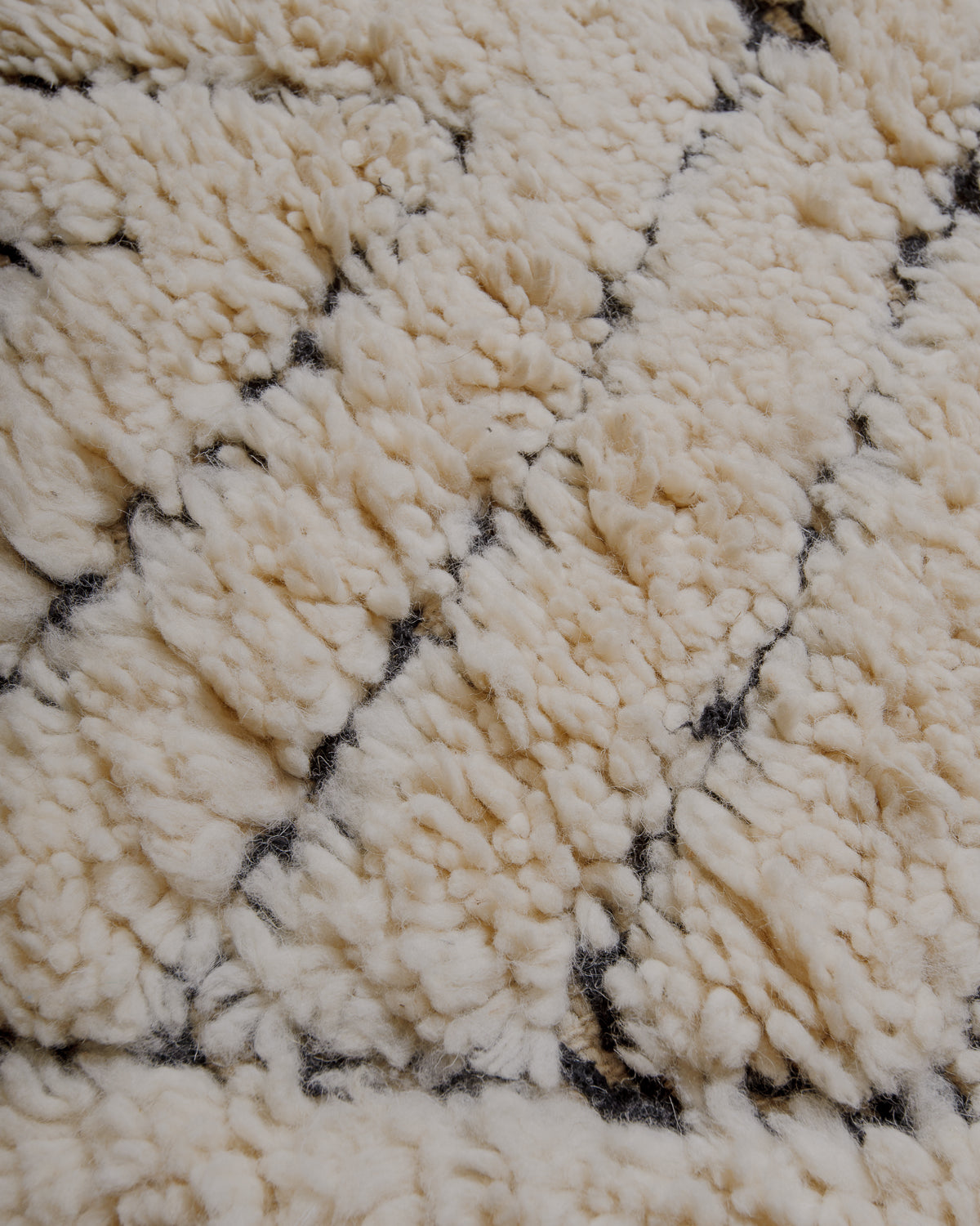 Fluffy cream wool pile with black embroidered lines .