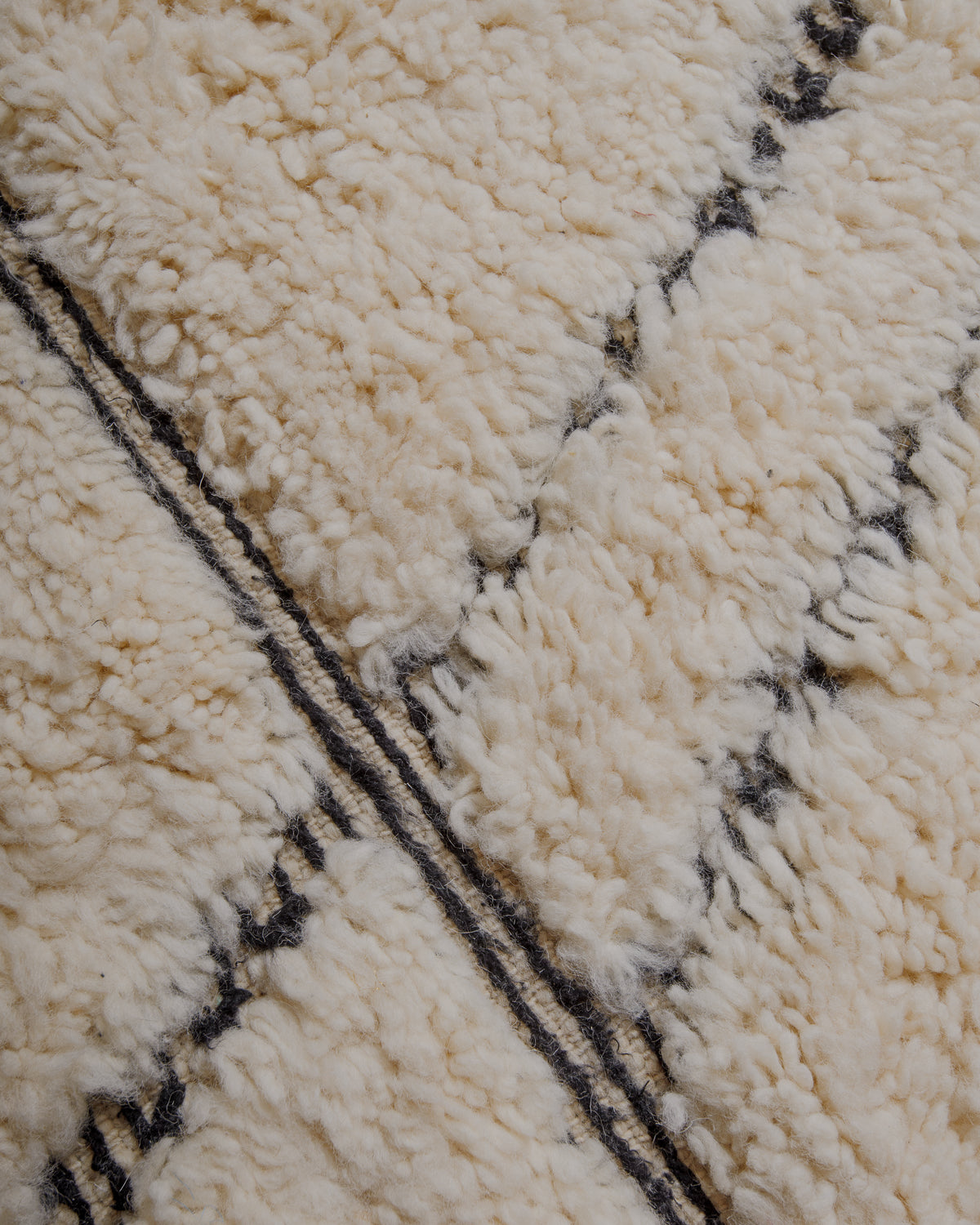 Fluffy cream wool pile with black embroidered lines .