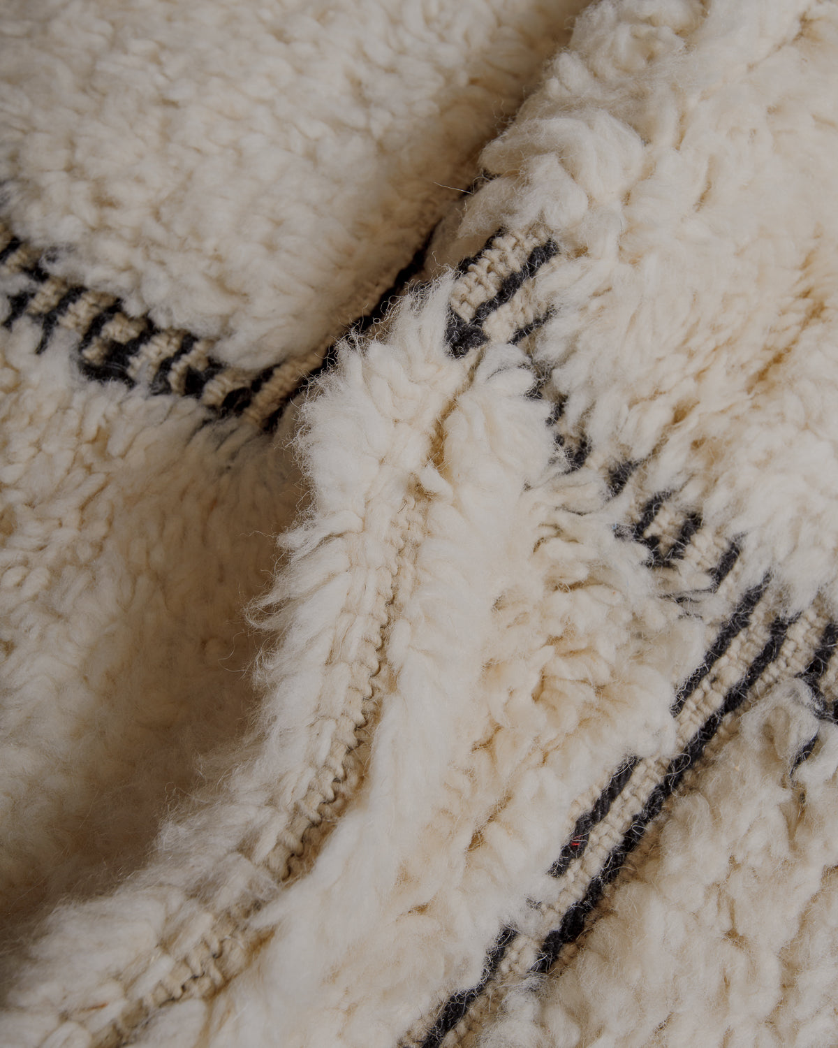 Fluffy cream wool pile with black embroidered lines .