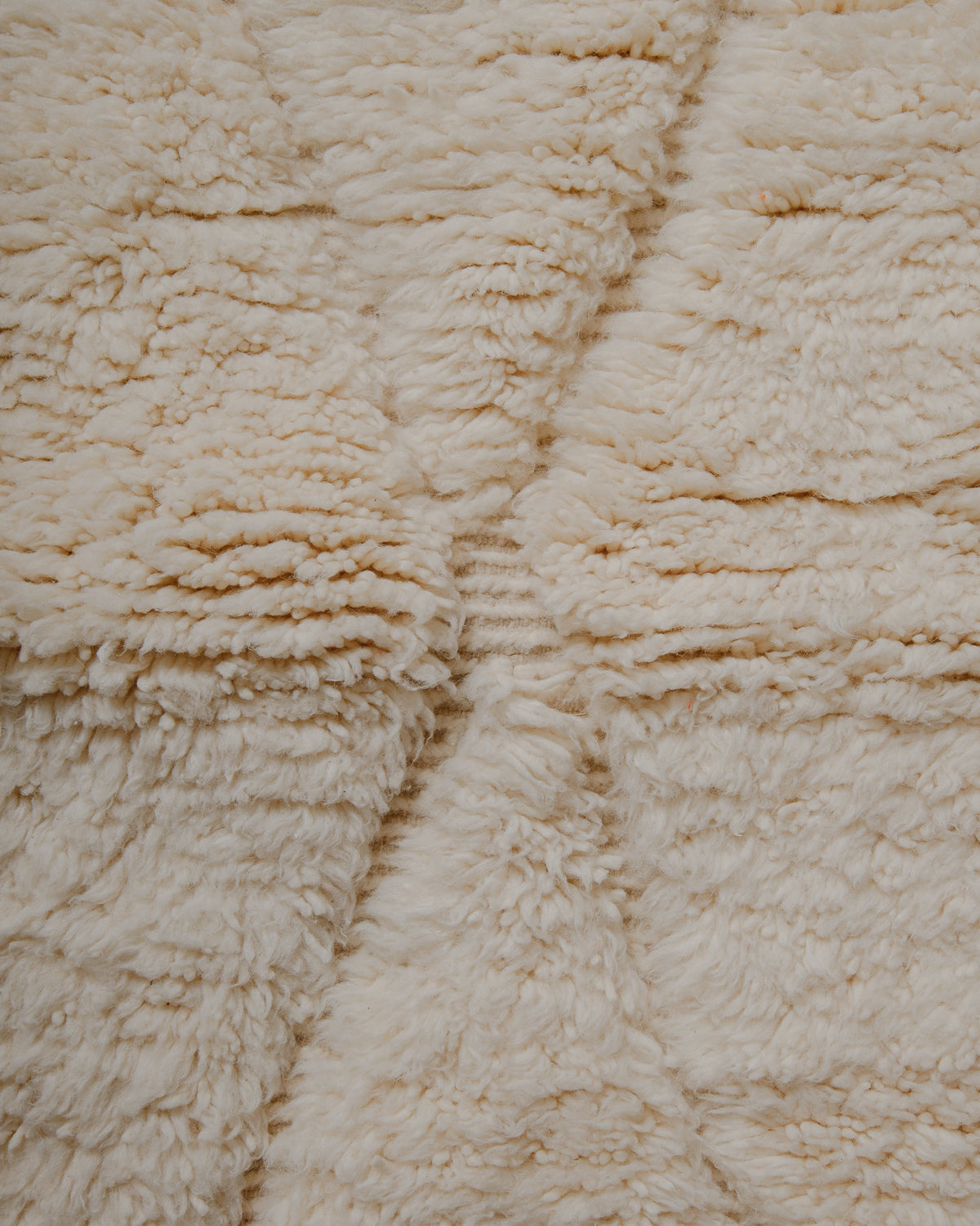 Detail of fluffy cream wool rug with woven lines.