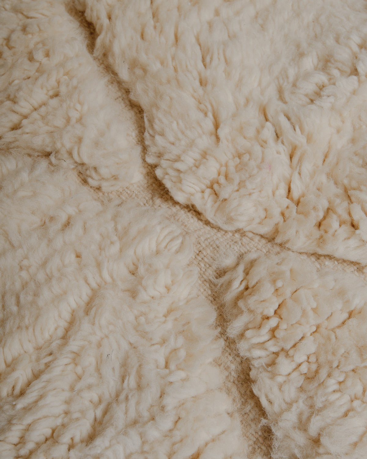 Detail of fluffy cream wool rug with woven lines.