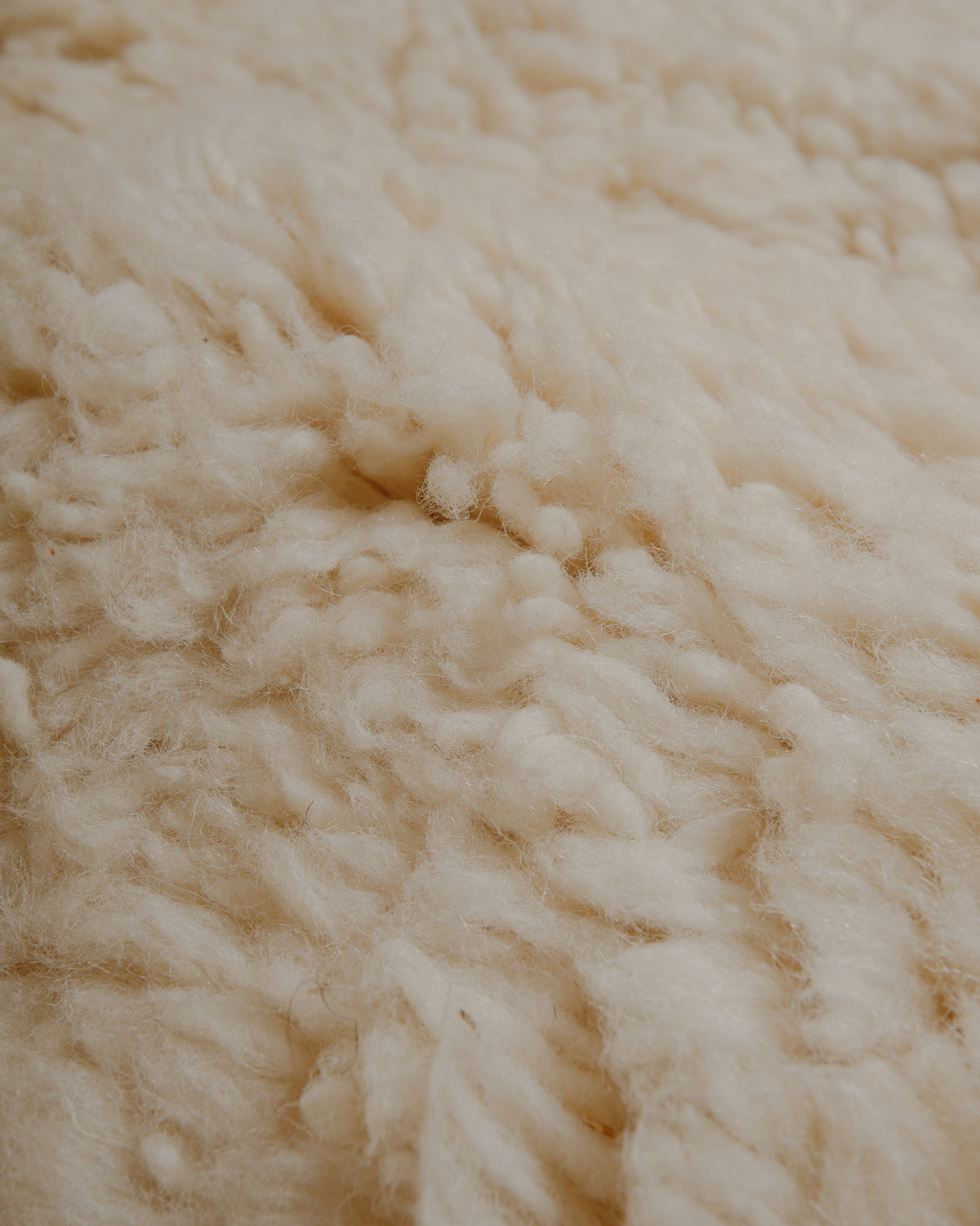 Close up of surface of fluffy cream wool rug.
