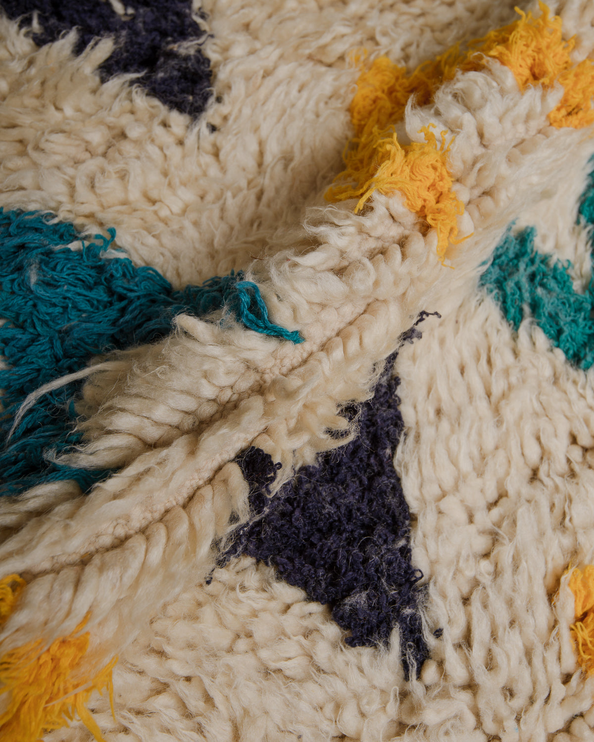 Close up of vintage rug made of cream wool and colourful cotton with a fluffy, shaggy texture.