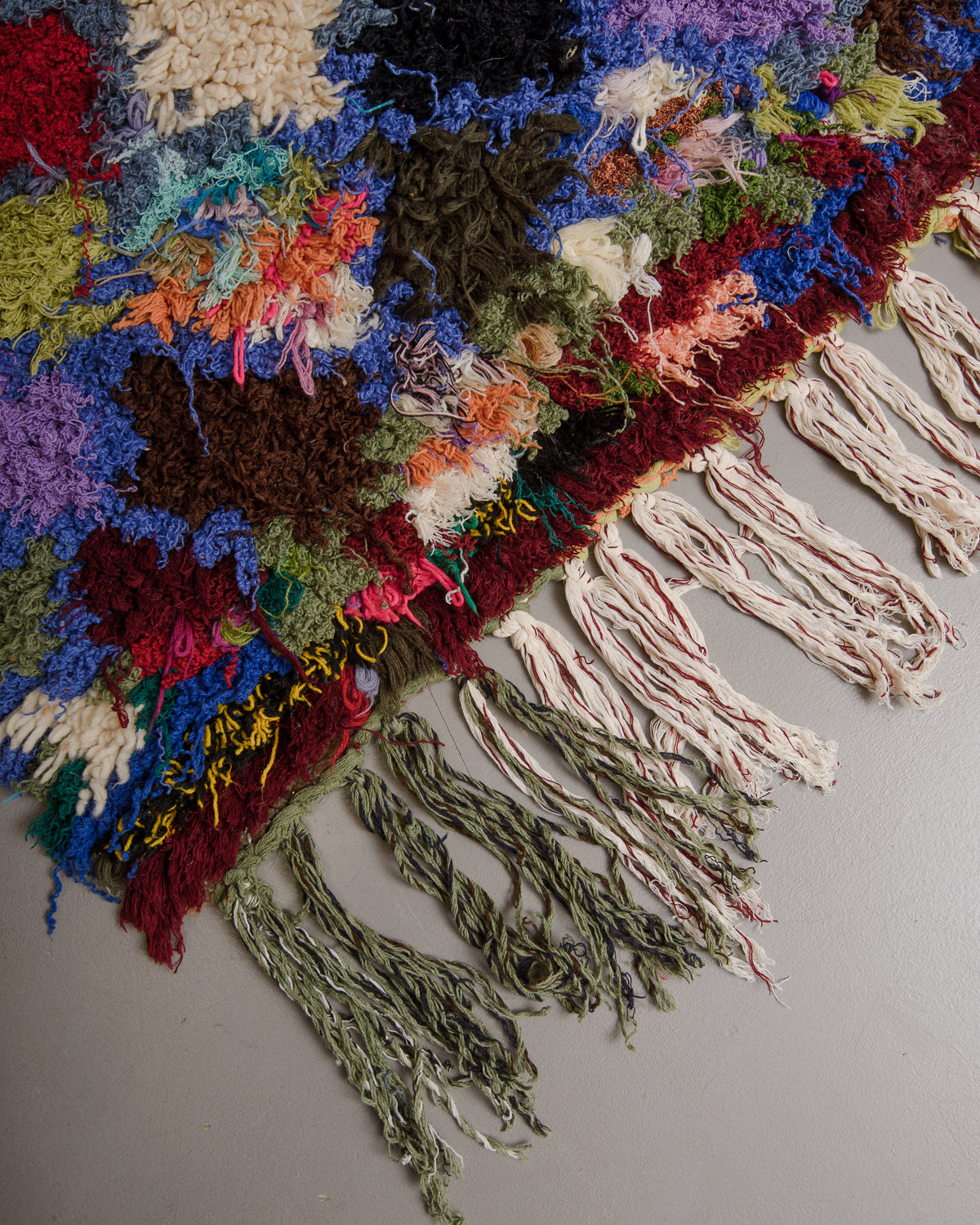 Close up of vintage rug with a shaggy texture and cotton tassels.