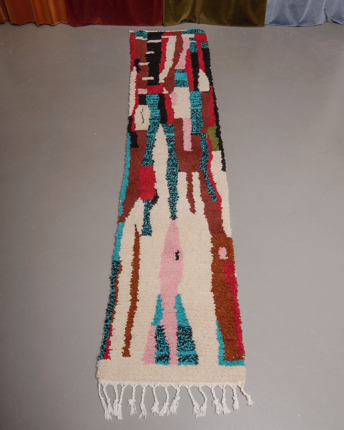 Vintage Berberlin boujaad runner rug on grey floor in front of velvet curtains.