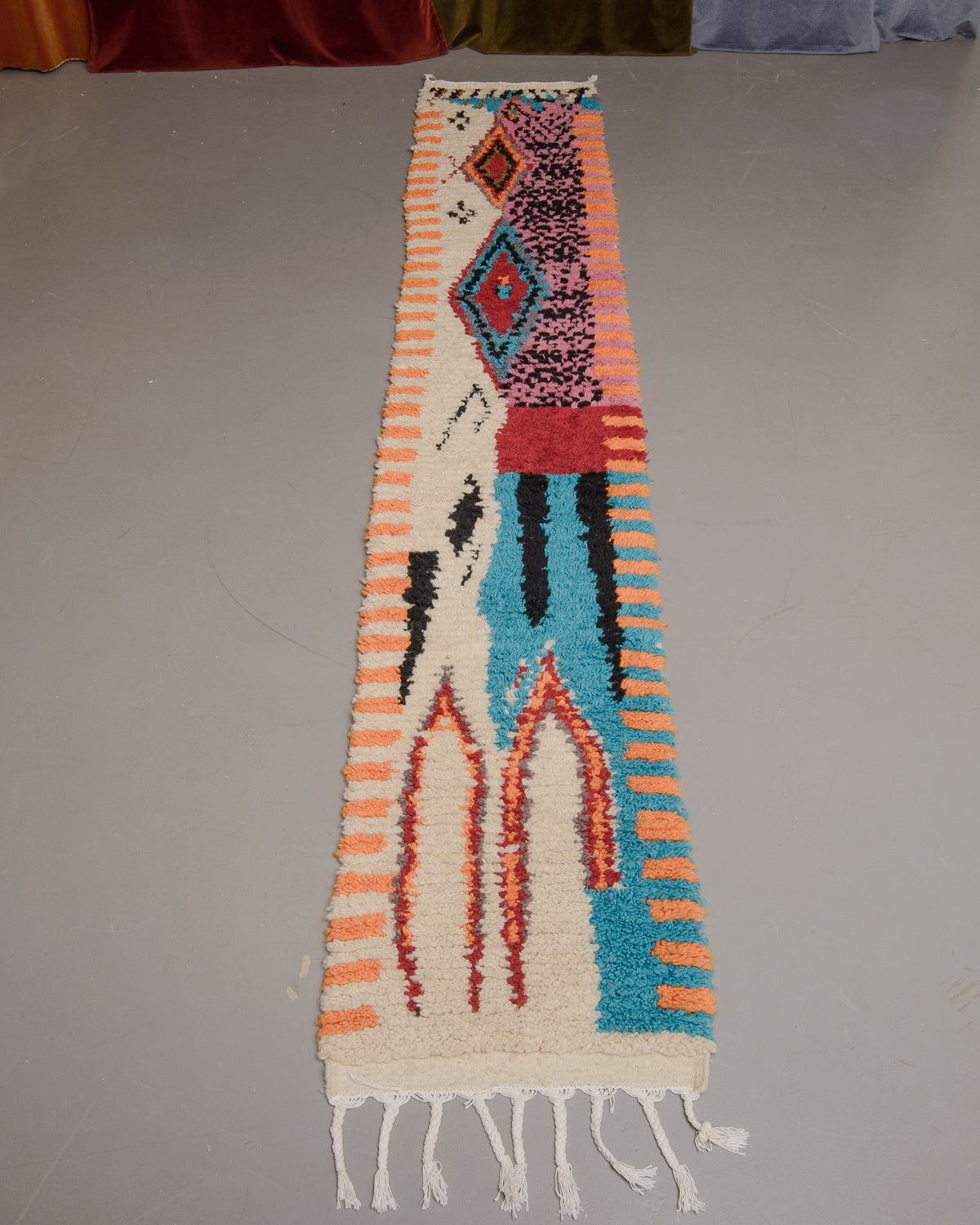 Vintage Berberlin boujaad runner rug on grey floor in front of velvet curtains.