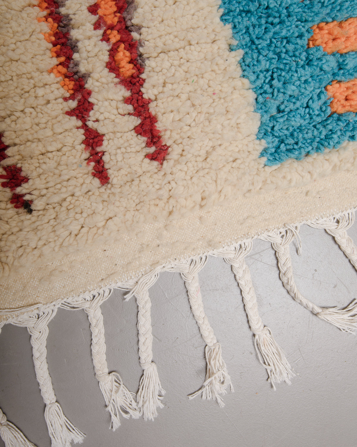 Edge of boujaad rug with white cotton tassels.