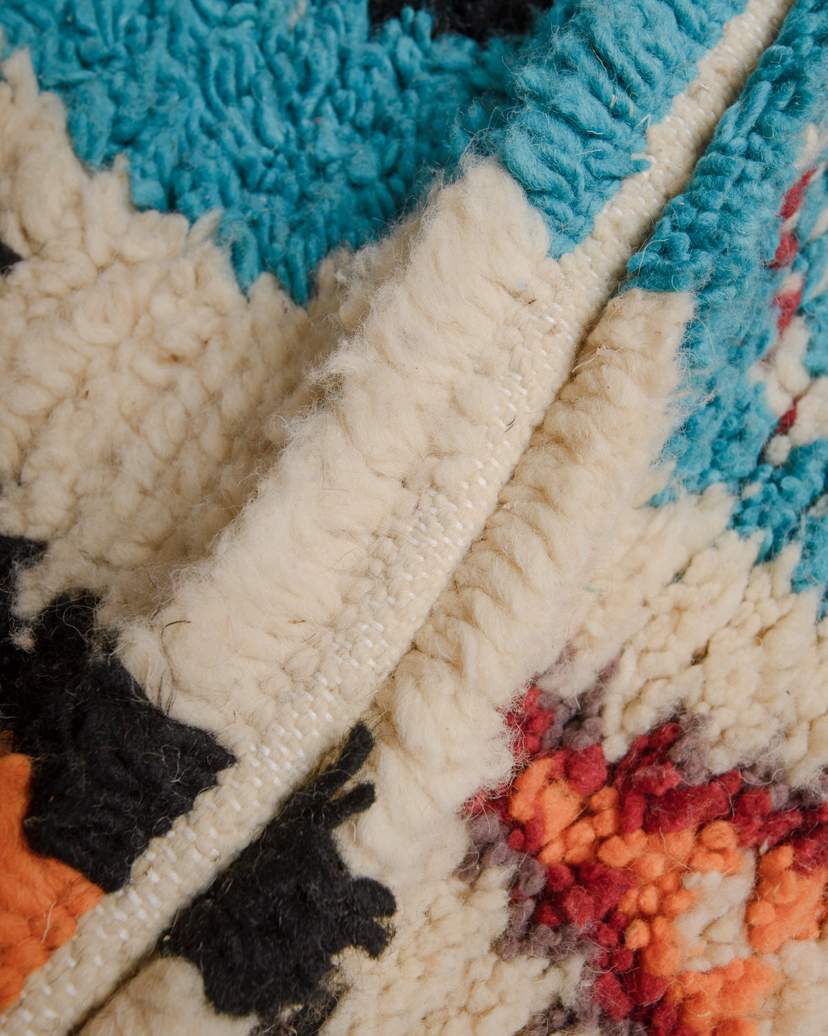 Close up of Boujaad rug with blue, black, taupe, red, orange and cream wool.