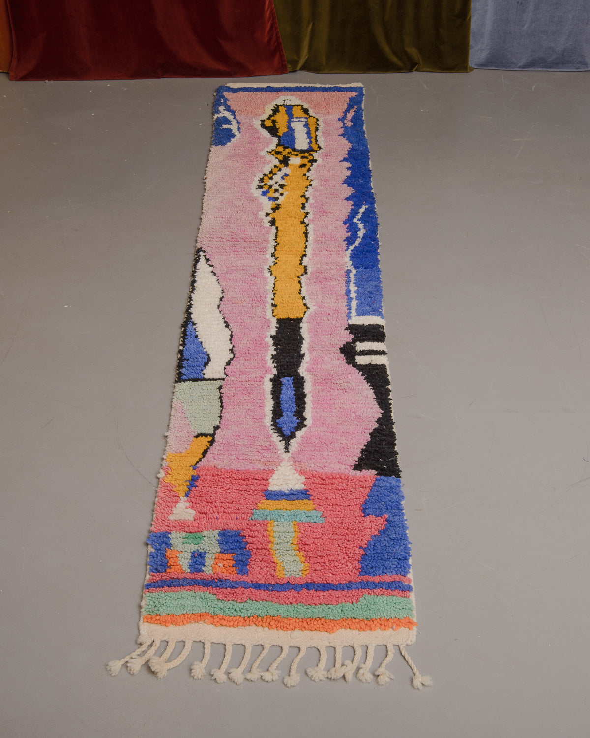 Vintage Berberlin boujaad runner rug on grey floor in front of velvet curtains.
