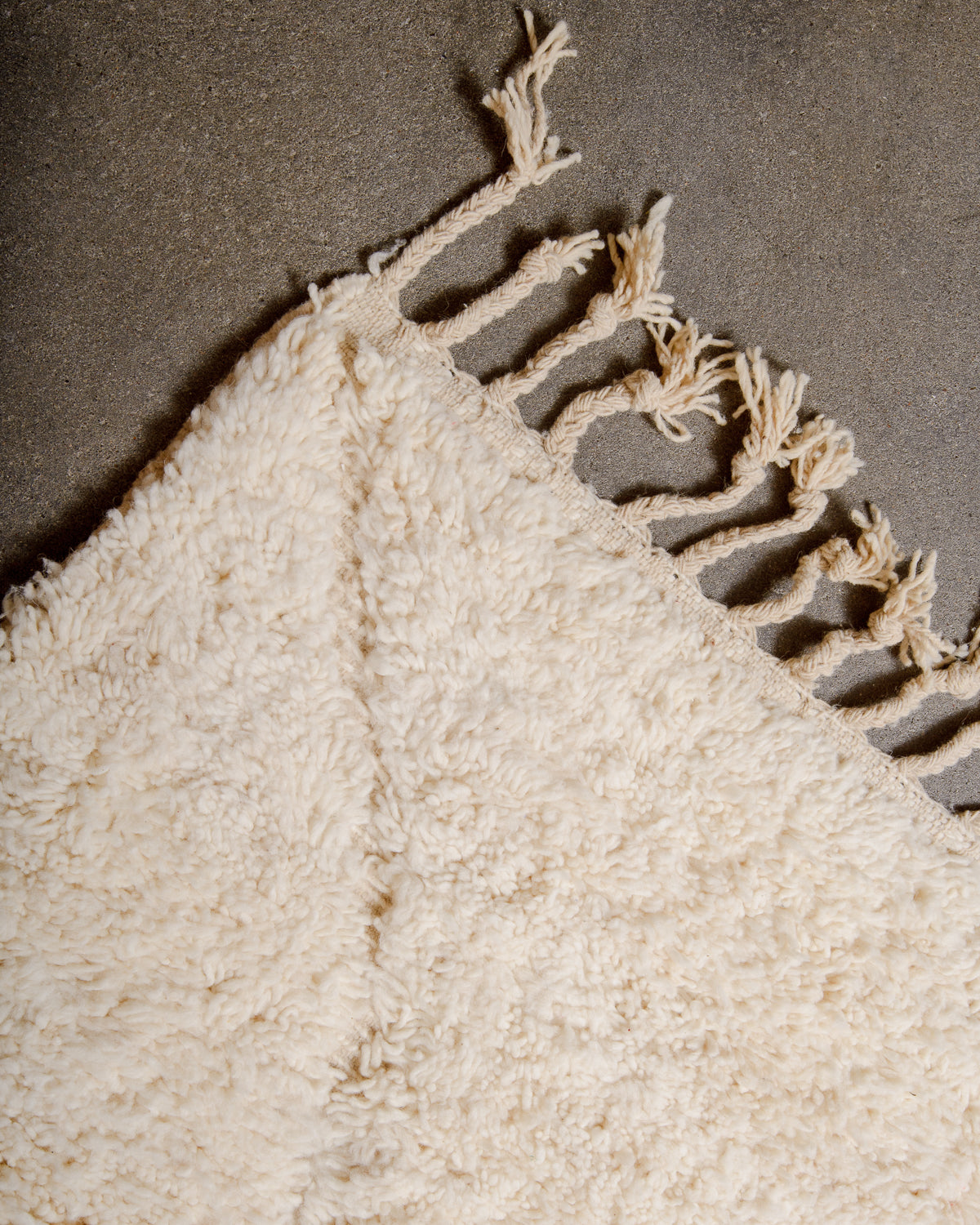 Corner of cream Beniourain rug with natural wool tassels. 