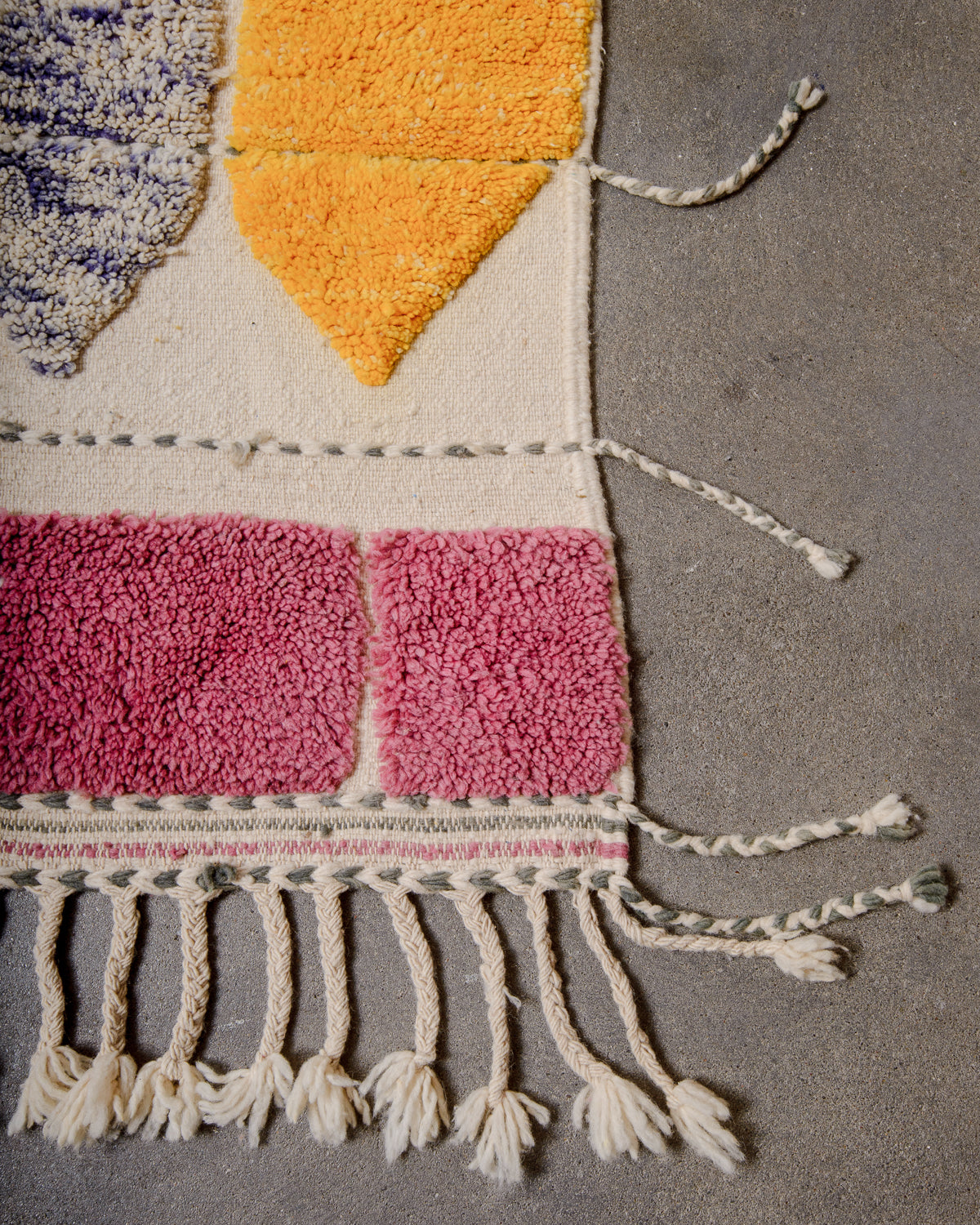 Corner of Berberlin Special Edition Beniourain rug with natural wool tassels on the end and spaced out grey and cream tassels on the sides.