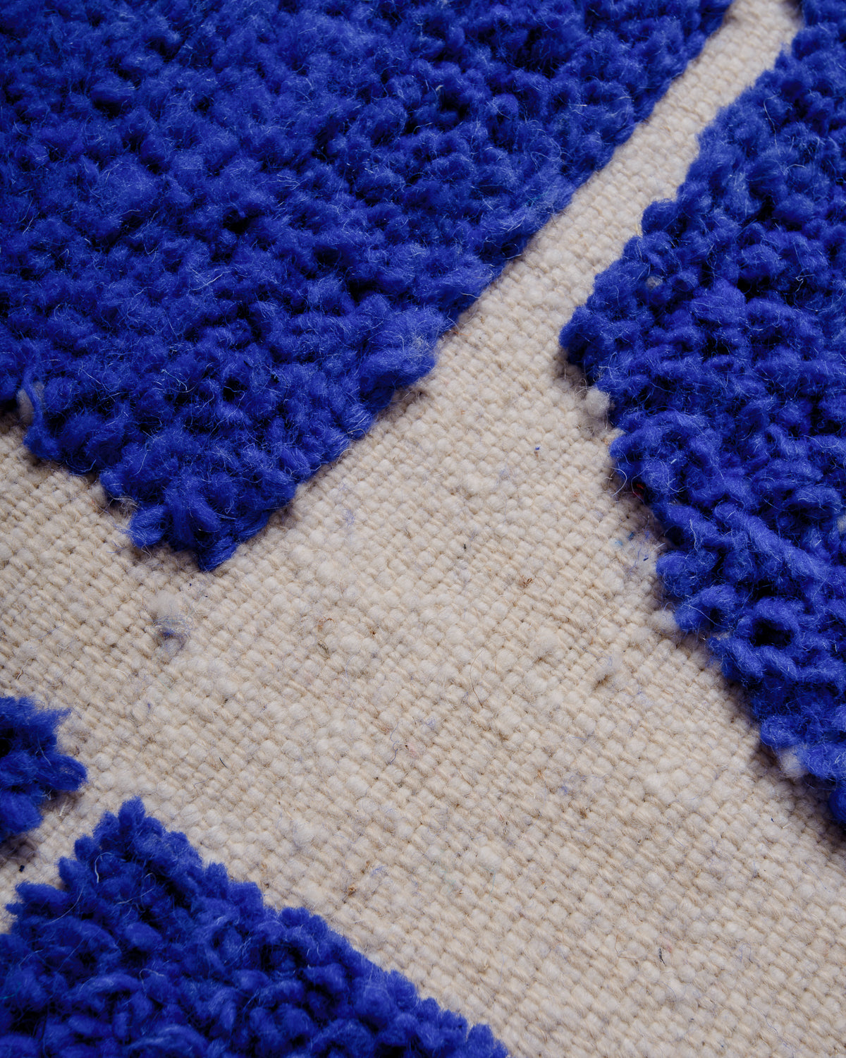 Close up of raised knotted areas and flat woven areas of cobalt blue and cream rug.