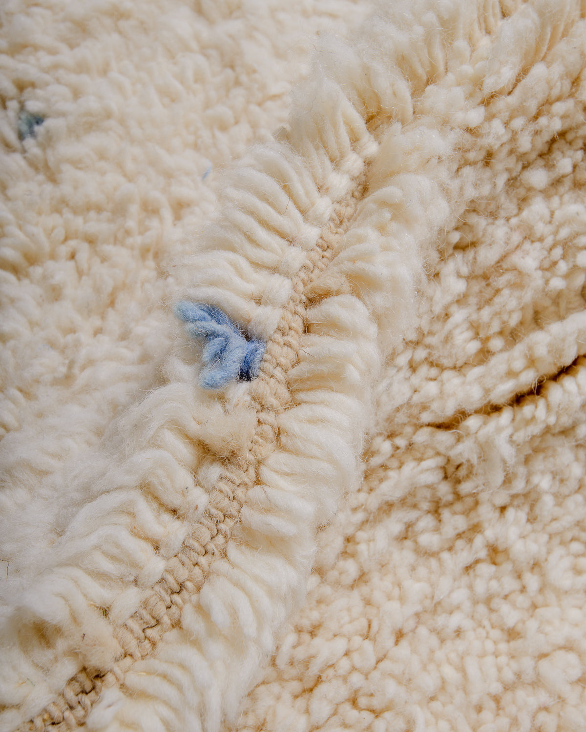 Detail of cream wool rug showing the density of the wool and coloured strands that make up the polka dots. 