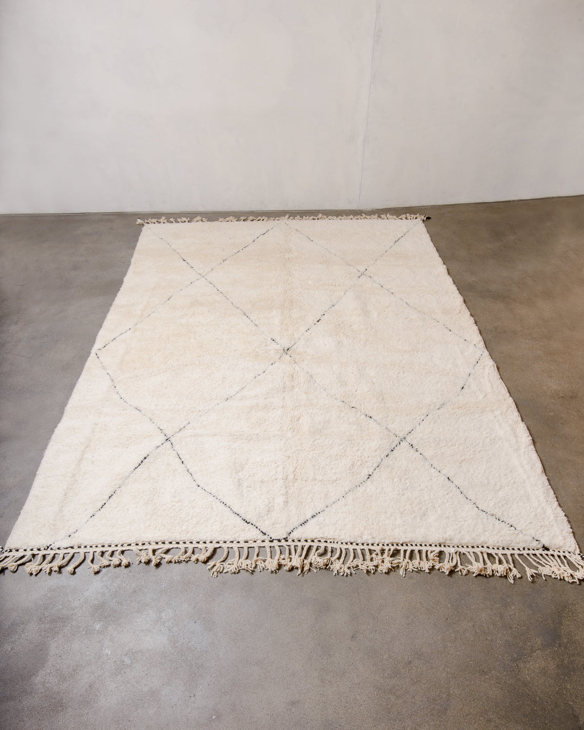 Cream Berber rug with black diamond design laying flat on floor. 