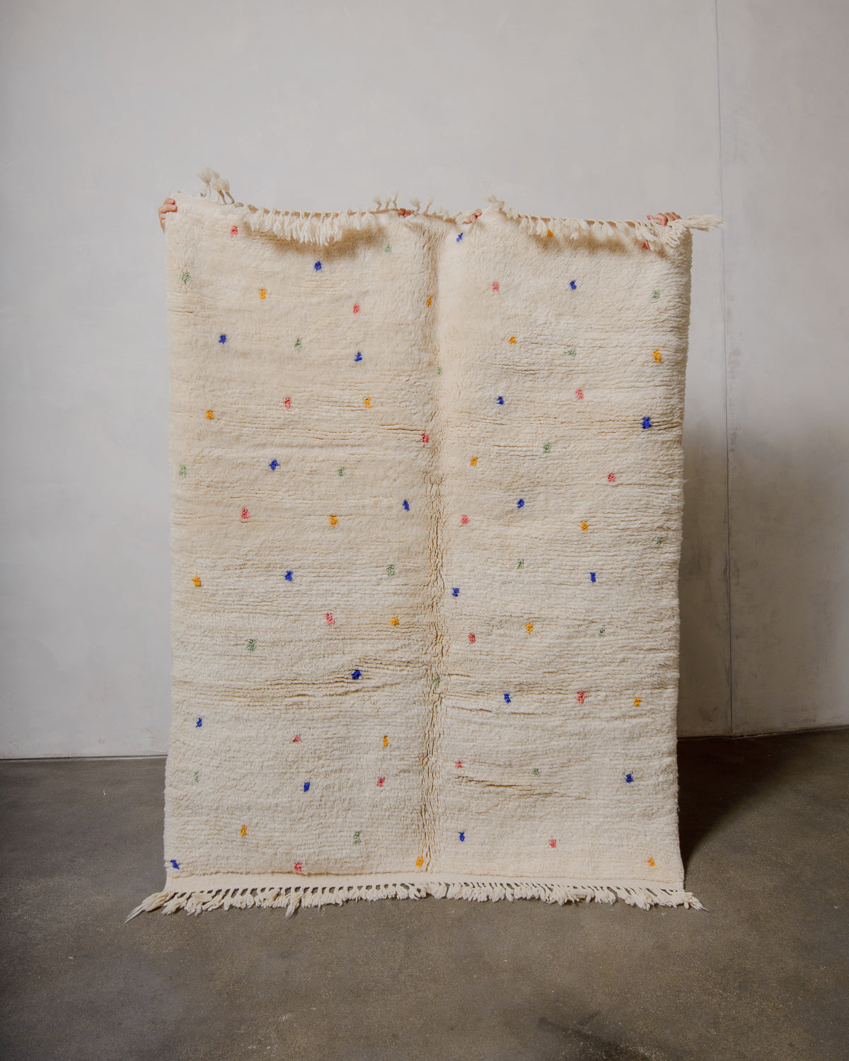 Cream wool rug with colourful polka dots on a plain background