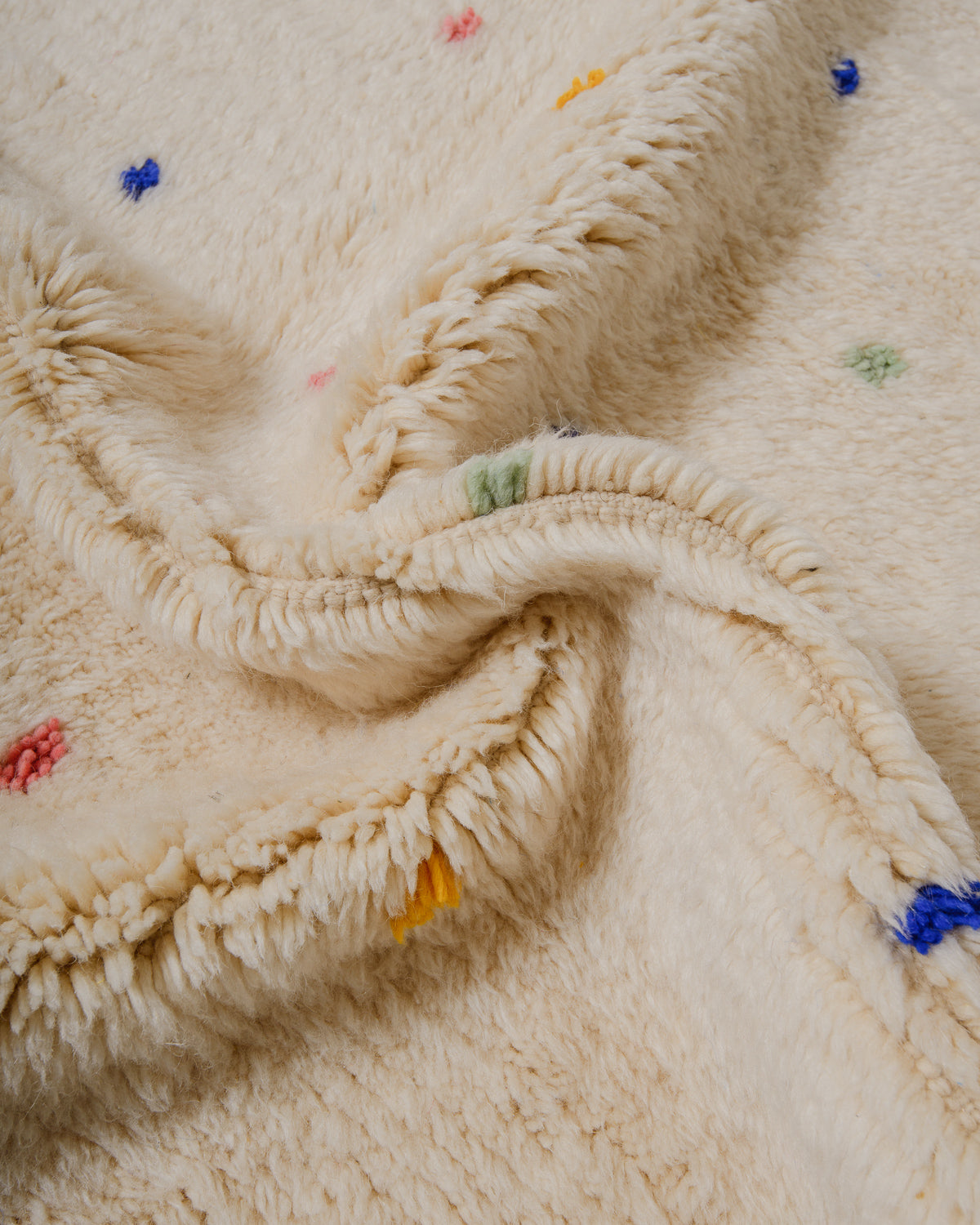 Close-up of cream wool rug with colourful dots.