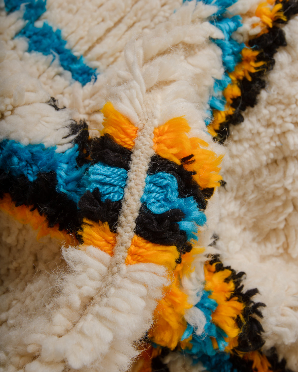 Close-up of Azilal rug with colourful threads in blue, yellow, and black.
