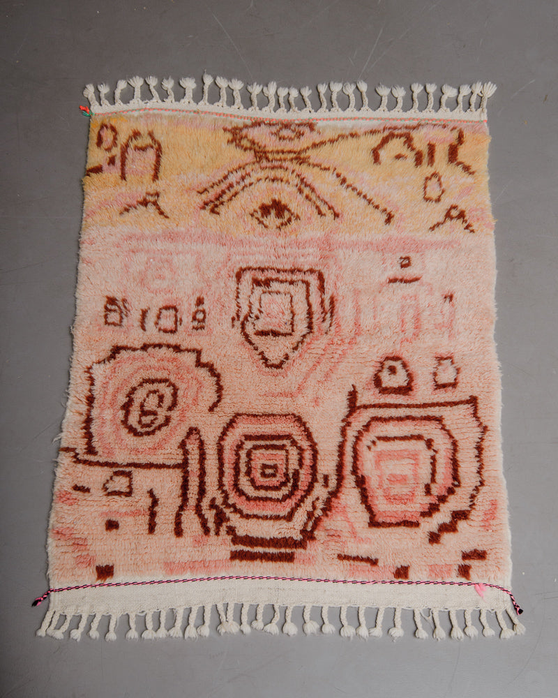 Berberlin Finest azilal rug in pink and orange with brown patterns laying on grey floor. 