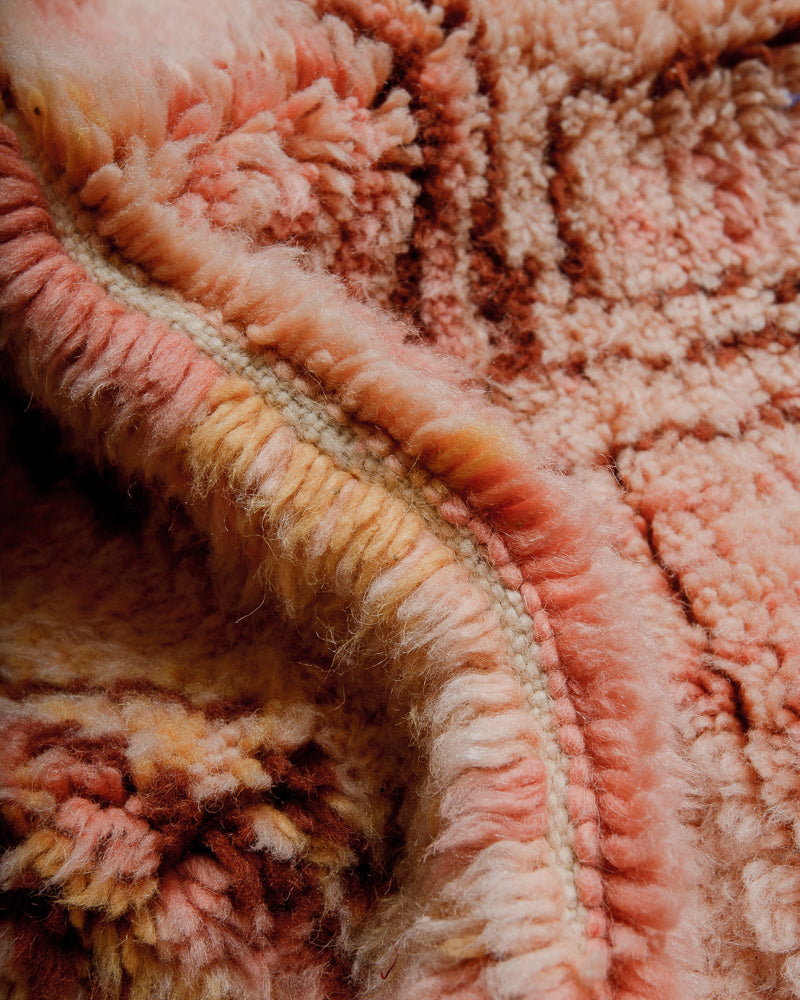 Close up of wool rug with shades of pink, orange and brown.