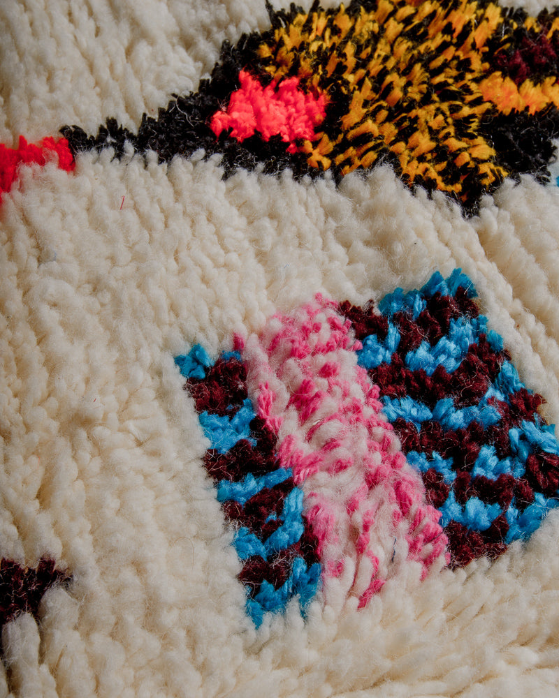 Surface of azilal rug with cream wool and coloured cotton accents.