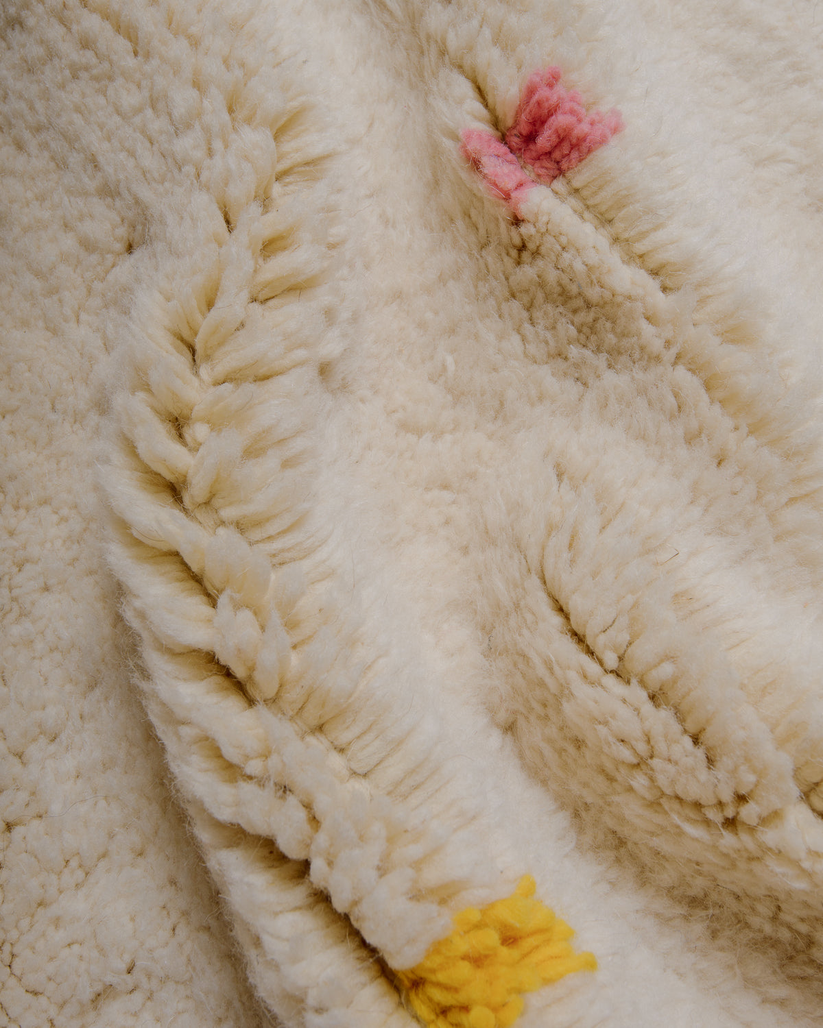 Close-up of cream wool rug with colourful dots.