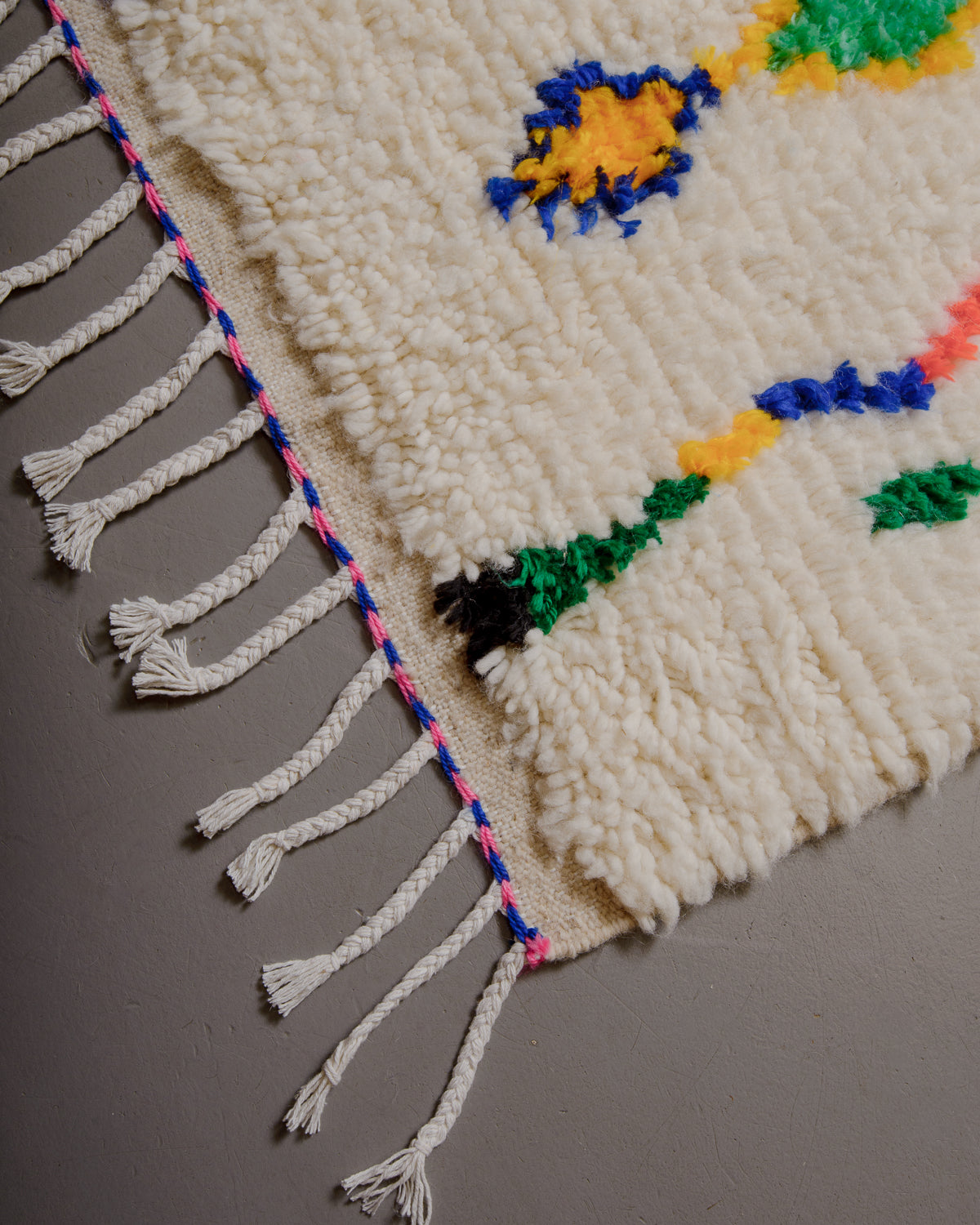 Corner of azilal rug with white cotton tassels.