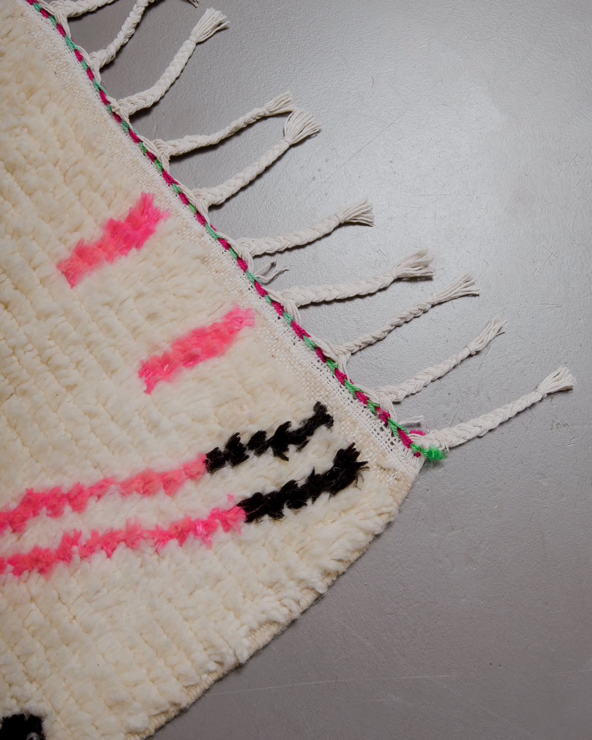 Corner of azilal rug with white cotton tassels.