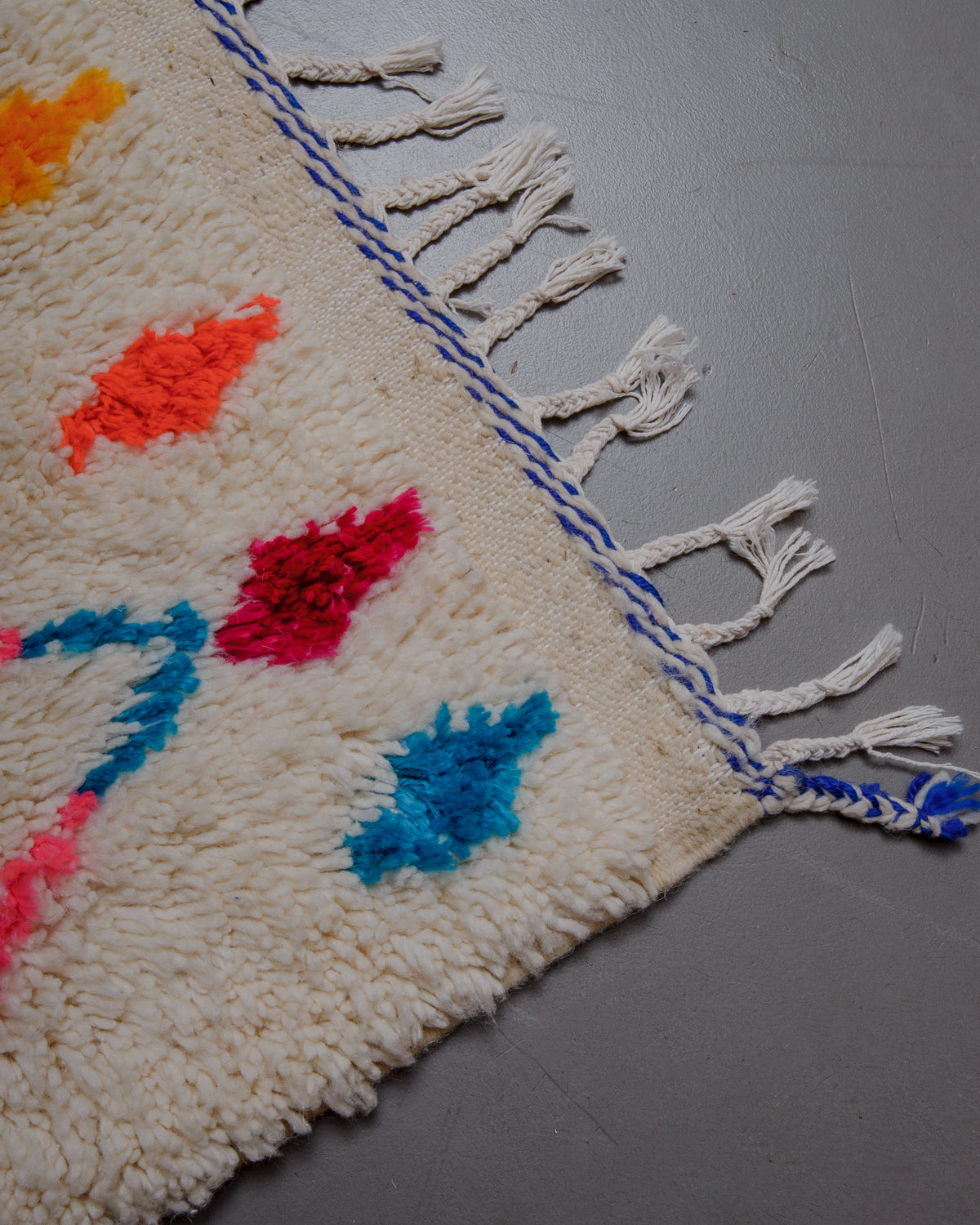 Corner of azilal rug with white cotton tassels.