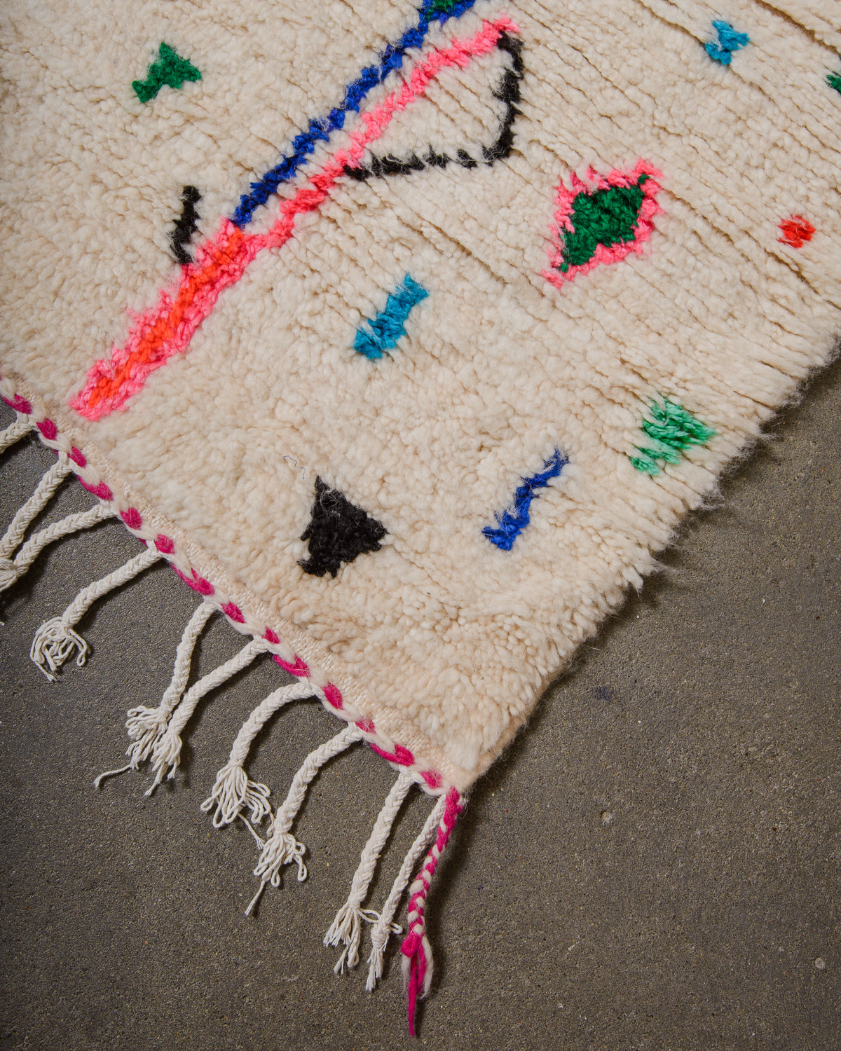 Corner of Azilal run with cream wool and white cotton across the edge and fuchsia trim.