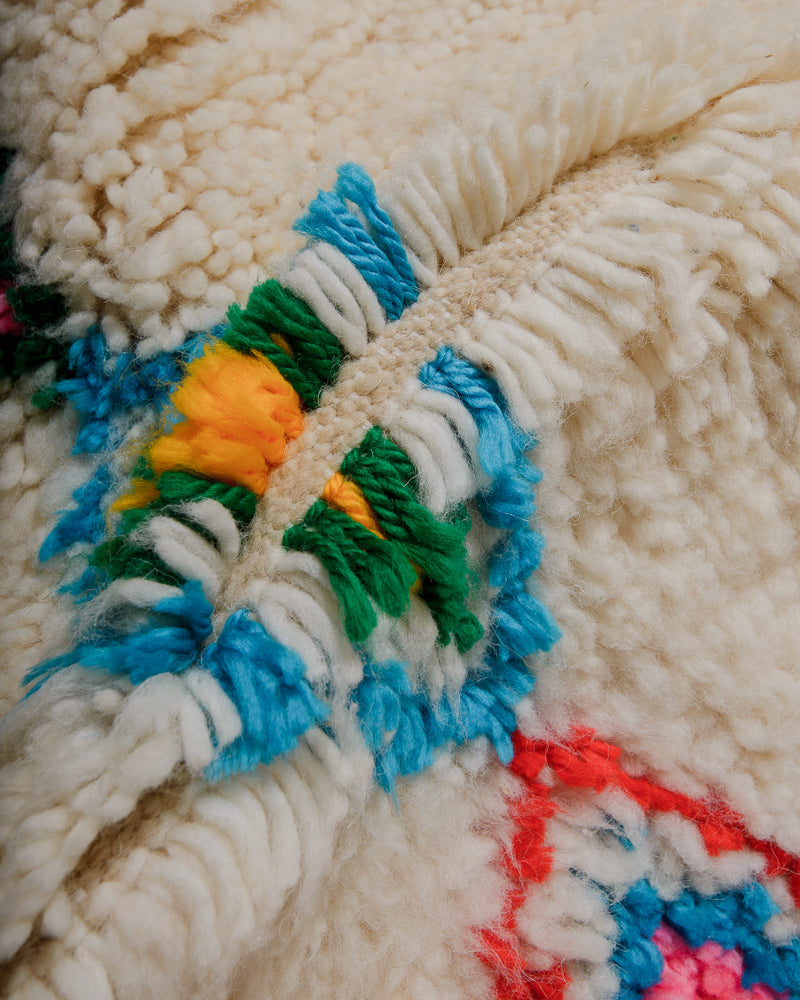 Close-up of a textured wool rug with colourful yarn and creamy sheeps wool.
