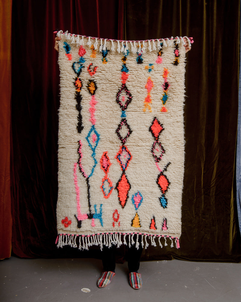 Small Berberlin Azilal rug held up in front of a velvet curtain