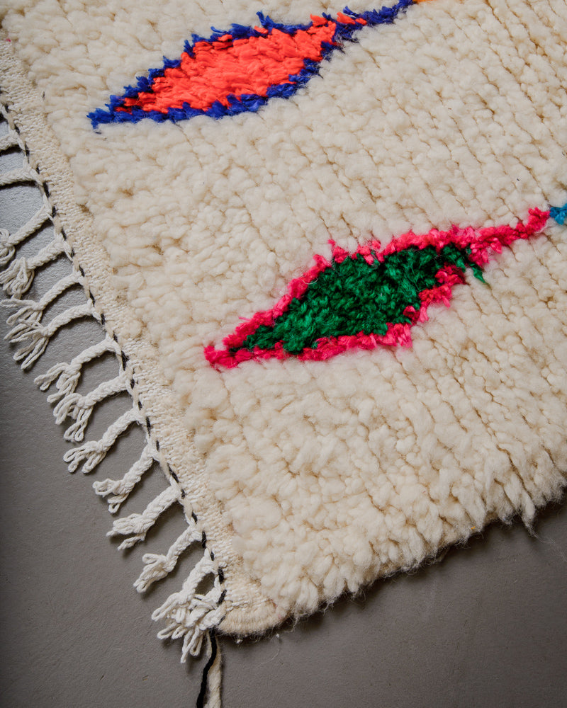 Corner of Berberlin Azilal rug with cream wool and colourful cotton and white cotton tassels.
