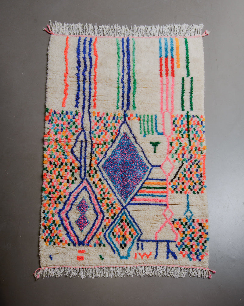 Berberlin Azilal rug with cream wool and colourful cotton flat on grey floor. 