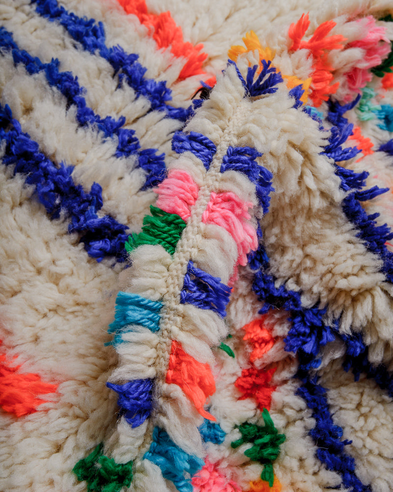 Surface of rug with colourful cotton in blue, pink, orange and green.