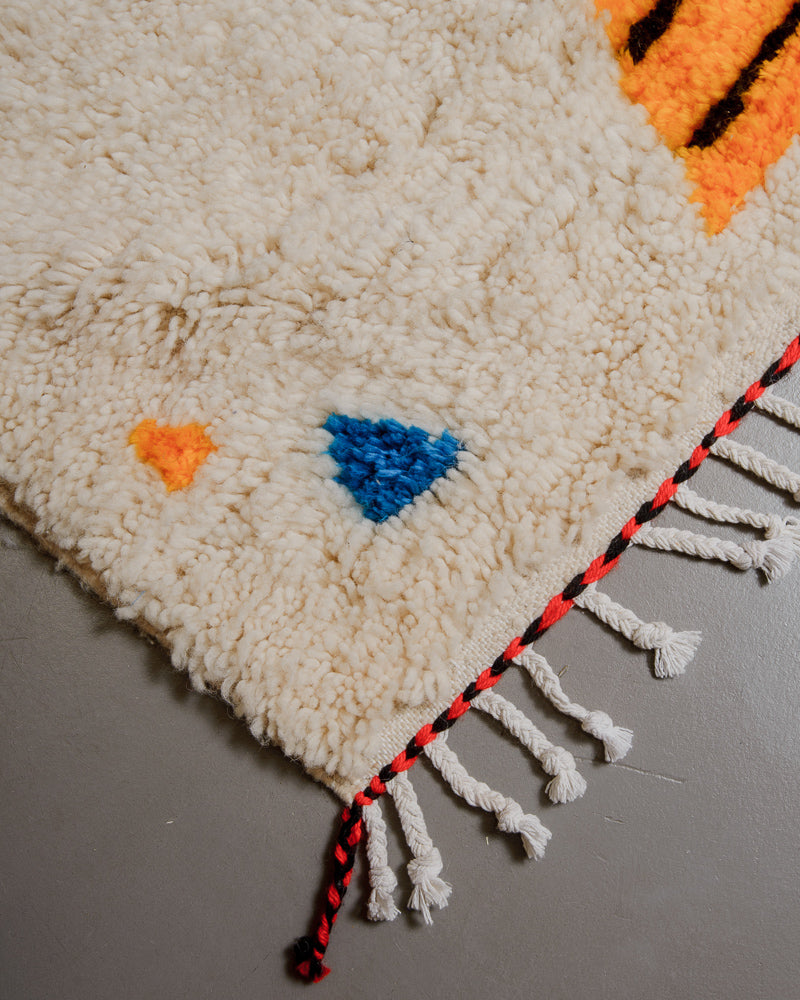 Corner of Berberlin Azilal rug with cream wool and colourful cotton and white cotton tassels.