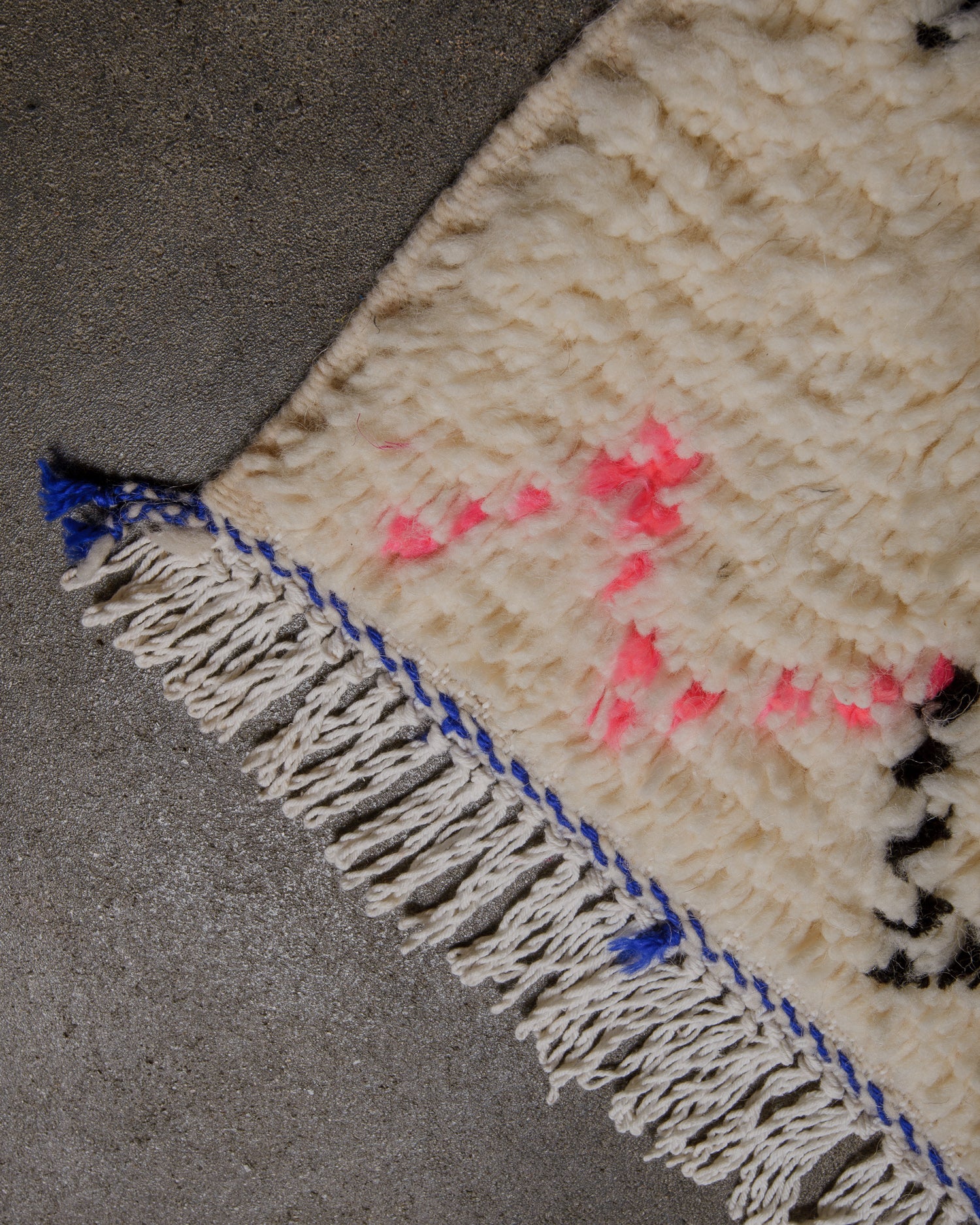 Corner of azilal rug with white cotton tassels. 
