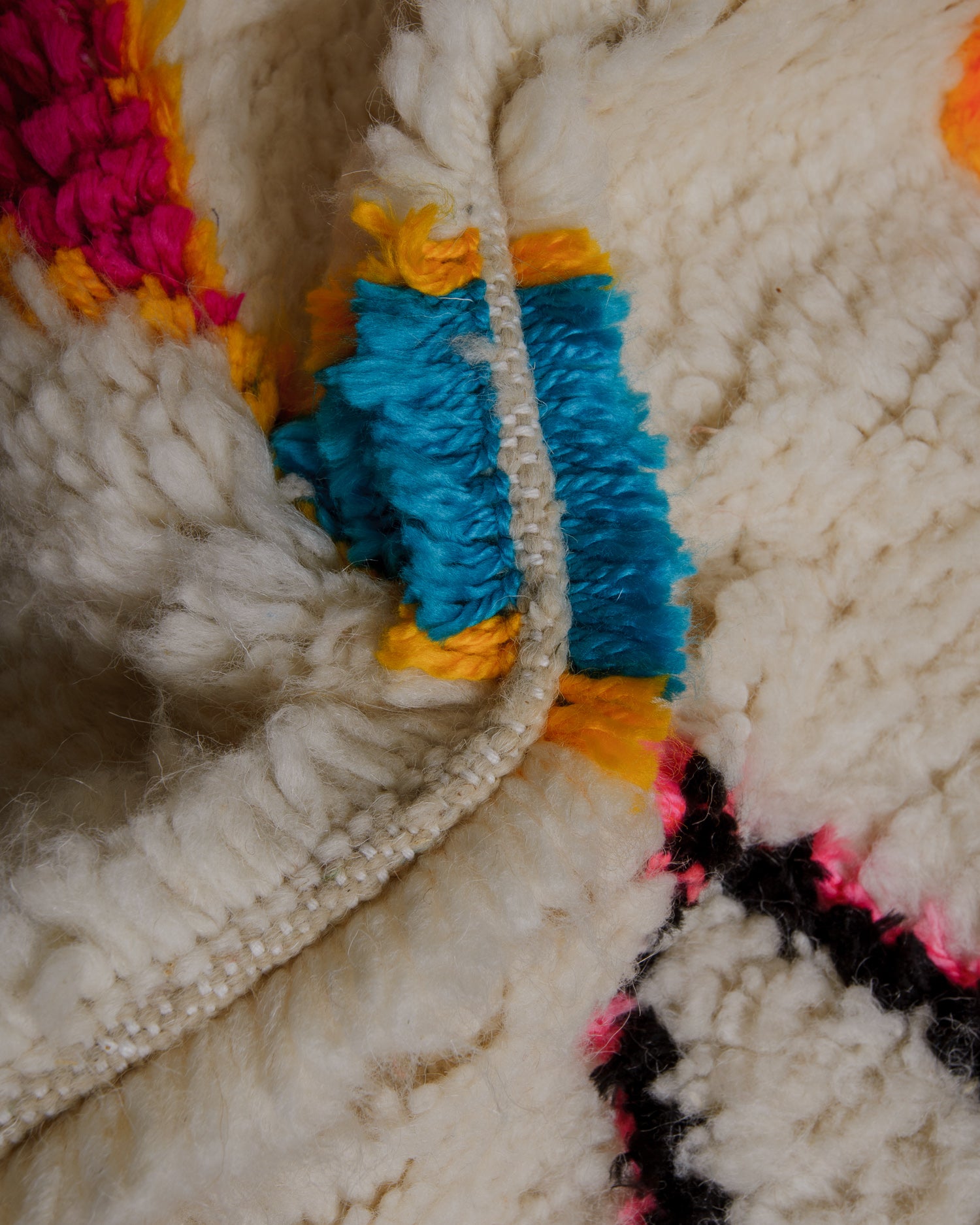 Close up of azilal rug with fluffy pile in cream, blue and yellow.