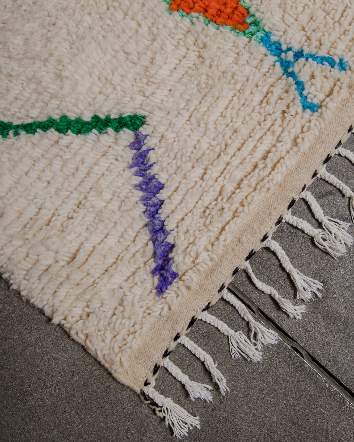Corner of azilal rug with white cotton tassels. 